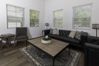 A black couch with a coffee table in front of it.